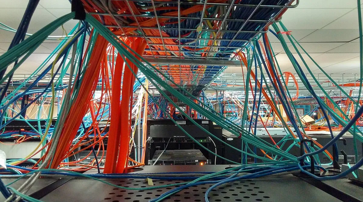 Tavan kablo tavalarından sarkan düzensiz Ethernet ve fiber kablolar